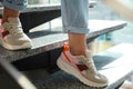 Young woman wearing stylish sneakers on stairs indoors, closeup