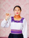 Young woman wearing traditional andean dress, facing camera doing sign language word for hello Royalty Free Stock Photo