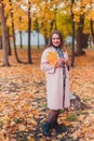 Young woman wearing trendy pink coat in autumn park. Looking at camera. Autumn season.