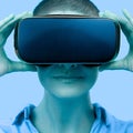 Young woman wearing virtual reality goggles. Woman wearing VR glasses over blue background. VR experience concept, close up. Royalty Free Stock Photo