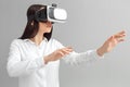 Freestyle. Woman in virtual reality headset standing isolated on gray playing concentrated Royalty Free Stock Photo