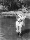 Young woman wearing waders holding a fishing rod