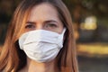 Young woman wearing white cotton mouth nose mask, nice bokeh in background, closeup face portrait