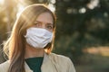 Young woman wearing white cotton virus mouth nose mask, nice bokeh in background, closeup face portrait