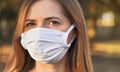 Young woman wearing white cotton virus mouth nose mask, nice bokeh in background, closeup face portrait Royalty Free Stock Photo