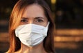 Young woman wearing white cotton virus mouth nose mask, nice bokeh, park afternoon sun, in background, closeup face portrait Royalty Free Stock Photo