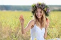 Young woman wearing wreath made of flowers in field on sunny day Royalty Free Stock Photo