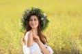 Woman wearing wreath made of beautiful flowers in field on sunny day Royalty Free Stock Photo