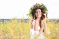 Young woman wearing wreath made of flowers in field on sunny day Royalty Free Stock Photo