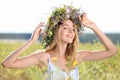 Young woman wearing wreath made of flowers in field on sunny day Royalty Free Stock Photo