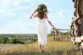 Young woman wearing wreath made of beautiful flowers outdoors on sunny day, back view Royalty Free Stock Photo