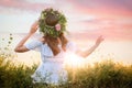 Young woman wearing wreath made of beautiful flowers outdoors on sunny day, back view Royalty Free Stock Photo