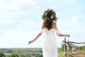 Young woman wearing wreath made of beautiful flowers outdoors on sunny day, back view Royalty Free Stock Photo