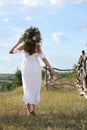 Young woman wearing wreath made of flowers outdoors on sunny day, back view Royalty Free Stock Photo