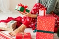 Young woman wearing xmas pajamas sitting on the floor amongst wrapped christmas presents, relaxing. Royalty Free Stock Photo