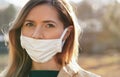 Young woman wears home made white cotton mouth face mask, wrong way, incorrect wearing - masks should cover nose as well