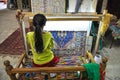 Young woman weaves a carpet on handloom