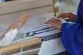 Young woman weaves a white cloth on a hand wood loom