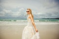 Young woman in wedding dress goes over sea turning back. bride on the beach. Royalty Free Stock Photo