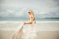 Young woman in wedding dress goes over sea turning back. bride on the beach. Royalty Free Stock Photo