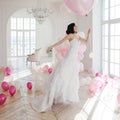 Young woman in wedding dress in luxury interior flies on pink and white balloons. Royalty Free Stock Photo