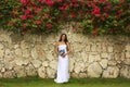 Young woman in wedding dress posing in front of the stone wall