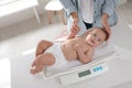 Young woman weighting her cute baby at home, above view. Health care Royalty Free Stock Photo