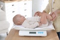 Young woman weighting her cute baby at home, closeup. Health care Royalty Free Stock Photo