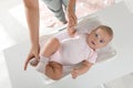 Young woman weighting her cute baby at home, top view. Health care Royalty Free Stock Photo