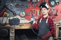 Young woman welder smiles and holds protective mask in hand on background industrial workplace or garage. Concept small