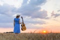 Young woman in wheat field with acoustic guitar at sunset Royalty Free Stock Photo