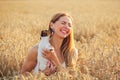 Young woman in wheat field, lit by afternoon sun, trying to pose