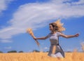 Young woman at the wheat field under the blue sky at the sunny day Royalty Free Stock Photo