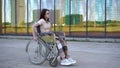 Young woman in a wheelchair. A girl rides in a wheelchair against the background of a glass building. Special transport