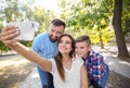 Young woman in wheelchair with her family taking selfie outdoors Royalty Free Stock Photo