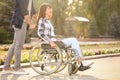 Young woman in wheelchair and her husband outdoors Royalty Free Stock Photo