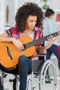 Young woman in wheelchair playing guitar at home Royalty Free Stock Photo