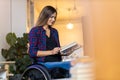 Woman in wheelchair reading a book at home Royalty Free Stock Photo