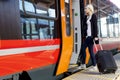 Young Woman With Wheeled Luggage Boarding Train