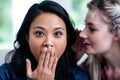 Young woman whispering to surprised female friend Royalty Free Stock Photo