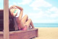 Young woman whit sun hat lying on sun bad enjoys sunbath at the beach with the sea and sky in the background on hot summer day