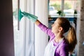 Young woman in white apron cleaning windows. Royalty Free Stock Photo