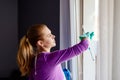 Young woman in white apron cleaning windows. Royalty Free Stock Photo