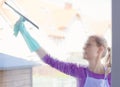 Young woman in white apron washing windows.