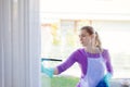 Young woman in white apron washing windows.