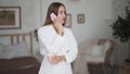 Young woman in white bathrobe drinks tea and talks on phone at home