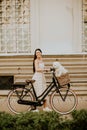 Young woman with white bichon frise dog in the basket of electric bike Royalty Free Stock Photo