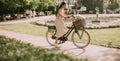 Young woman with white bichon frise dog in the basket of electric bike Royalty Free Stock Photo