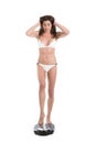 Young woman in white bikini near scale unhappy with her weight gesturing sadness. Fit and healthy concept. Isolated over white bac Royalty Free Stock Photo