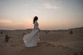 Young woman in white bridal dress alone in desert